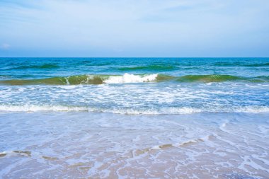 Açık mavi deniz dalgaları temiz kumsalda.