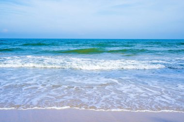 Açık mavi deniz dalgaları temiz kumsalda.