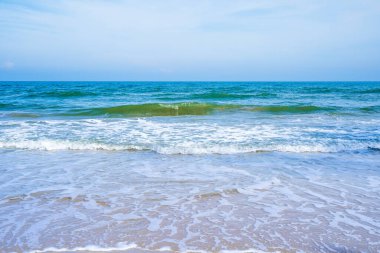 Açık mavi deniz dalgaları temiz kumsalda.