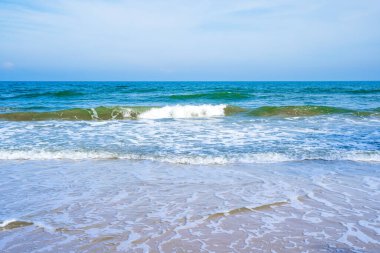 Açık mavi deniz dalgaları temiz kumsalda.