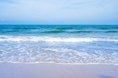 Açık mavi deniz dalgaları temiz kumsalda.