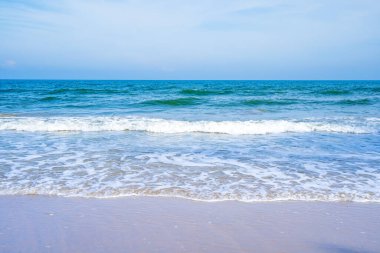 Açık mavi deniz dalgaları temiz kumsalda.