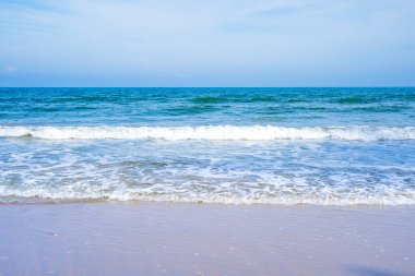 Açık mavi deniz dalgaları temiz kumsalda.