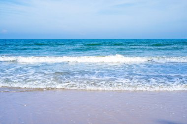 Açık mavi deniz dalgaları temiz kumsalda.