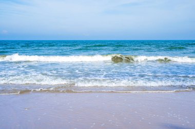 Açık mavi deniz dalgaları temiz kumsalda.
