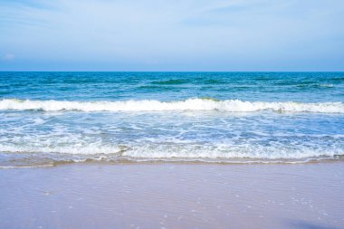 Açık mavi deniz dalgaları temiz kumsalda.