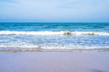 Açık mavi deniz dalgaları temiz kumsalda.