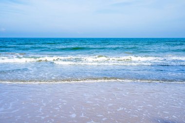 Açık mavi deniz dalgaları temiz kumsalda.