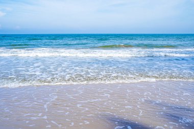 Açık mavi deniz dalgaları temiz kumsalda.