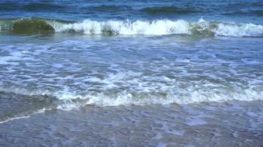 foamy waves rolling towards the sand beach, golden beach meeting deep blue ocean water and foamy waves. turquoise sea waves breaking on the sandy coastline. 