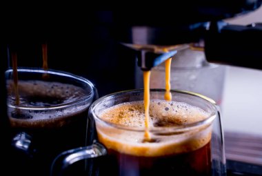 Kahve köpüğüne yakın çekim. Tam otomatik kahve makinesinden çıkan espresso kreması kahve makinesini fincana dönüştürür. yumuşak odak.