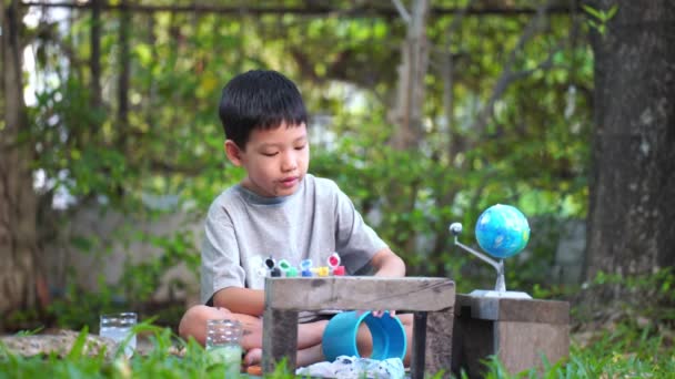 太陽系のおもちゃ 感覚活動 家庭での学習ツールを着色する集中アジアの少年 — ストック動画
