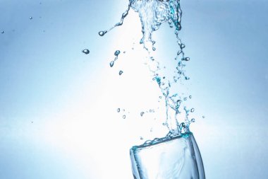 İçme suyu beyaz arka planda bardaktan sıçrıyor.