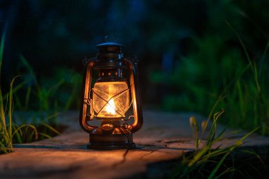 Ormanın eski ahşap zemininde antika bir gaz lambası gece kamp atmosferinde
