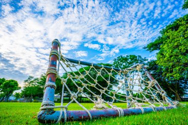 İp net gol, yeşil çimenli mini futbol sahası sade, eski usul minyatür cibinlikler örülmüş saman yığını gökyüzü ve beyaz bulutlar arka plan, seçici odaklanma, yumuşak odaklanma.