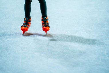 Açık havada buz pateni pistinde paten yapan genç bir kız, açık alanda buz pateni yapmayı düşünüyor.