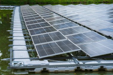 Gölde suyun üzerinde yüzen güneş panellerinin yan görünüşü, güneş ışığından elektrik üretmek, seçici odak, yumuşak odak.