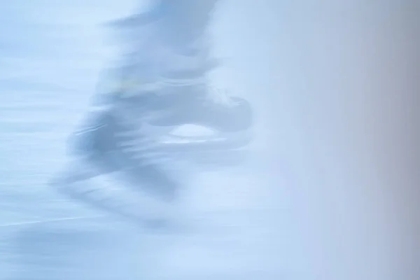 Açık hava buz pistinde paten hareketleri bulanıklaştı. Açık alanda paten yapan genç bir kız.