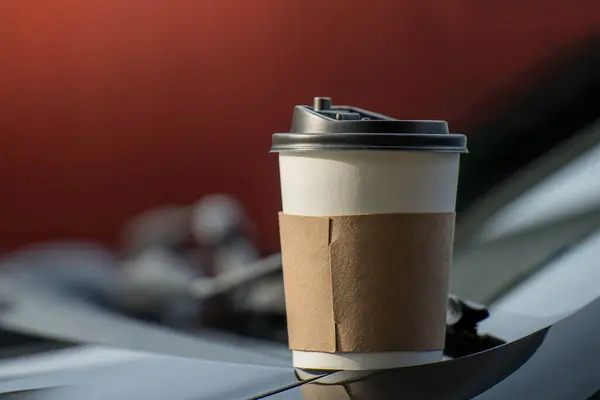 Paper coffee cups placed outside the car dashboard at sunrise in the morning,  selective focus, soft focus.