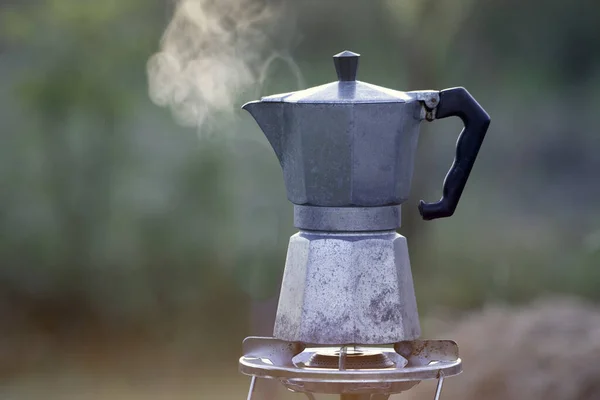 Moka pot and smoke, coffee bask on fire, In the forest at sunrise in the morning. soft focus. shallow focus effect.