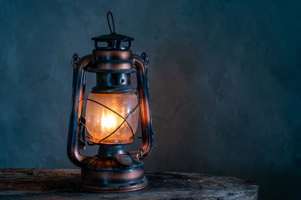 The old kerosene lamp on a wooden floor, old gray cement backdrop.