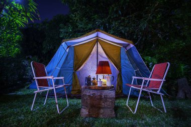 Antika kulübe çadırı, antika gaz lambası, retro sandalyeler, ormandaki kamp alanındaki ahşap masalarda açık kahve yapma tesisleri olan kamp çadırları..