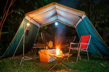 Antika kulübe çadırı, antika gaz lambası, retro sandalyeler, ormandaki kamp alanındaki ahşap masalarda açık kahve yapma tesisleri olan kamp çadırları..