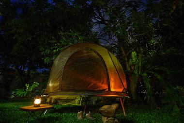 Ormandaki kamp alanındaki ahşap masalarda kahve yapma tesisleri olan kamp çadırları..