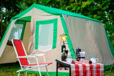 Eski ahşap masanın üzerine eski kabin çadırı, retro sandalyeler, kamp çadırları ve yumuşak odaklı çadırlar..