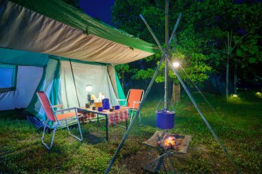 Geceleri kamp çadırları, eski kulübe çadırları, antika fenerler, retro sandalyeler ve ormandaki ahşap masalarda açık kahve yapma tesisleri.