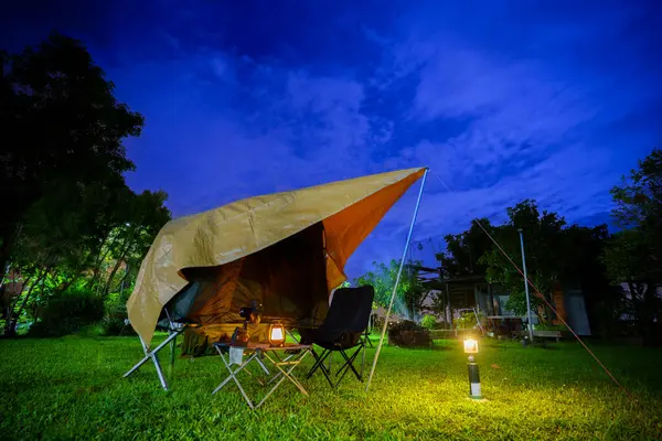Geceleri ormanın içinde kamp çadırları. Gökyüzü arka planında ay ışığı, antik fenerler.