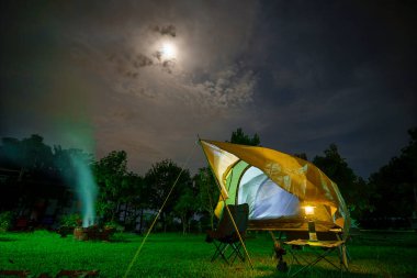 Geceleri ormanın içinde kamp çadırları. Gökyüzü arka planında ay ışığı, antik fenerler.,