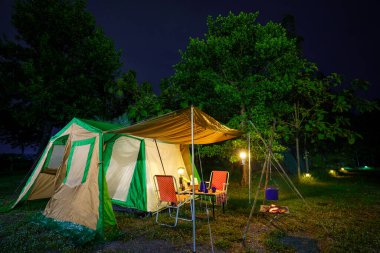 Geceleri kamp çadırları, eski kulübe çadırları, antika fenerler, retro sandalyeler ve ormandaki ahşap masalarda açık kahve yapma tesisleri.