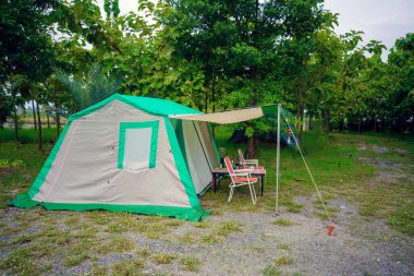 Geceleri kamp çadırları, eski kulübe çadırları, antika fenerler, retro sandalyeler ve ormandaki ahşap masalarda açık kahve yapma tesisleri.