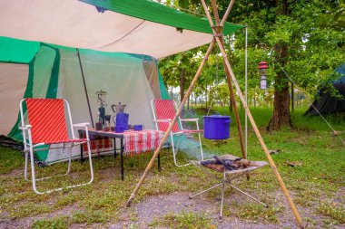Geceleri kamp çadırları, eski kulübe çadırları, antika fenerler, retro sandalyeler ve ormandaki ahşap masalarda açık kahve yapma tesisleri.