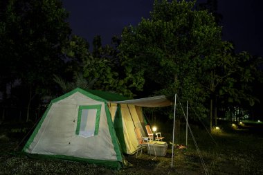 Geceleri kamp çadırları, eski çadırlar, antika fenerler, ormandaki eski sandalyeler.