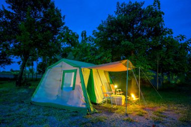 Geceleri kamp çadırları, eski çadırlar, antika fenerler, ormandaki eski sandalyeler.