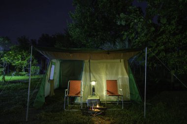 Geceleri kamp çadırları, eski çadırlar, antika fenerler, ormandaki eski sandalyeler.