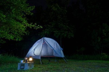 Geceleri ormanda kamp çadırları ve masaların üzerinde kahve yapma tesisleri.