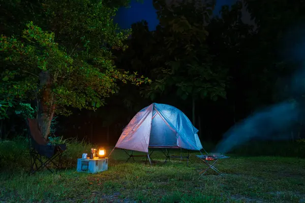 Geceleri ormanda kamp çadırları ve masaların üzerinde kahve yapma tesisleri.