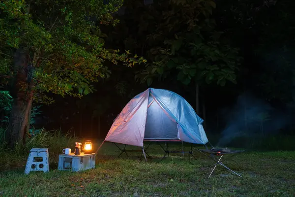 Geceleri ormanda kamp çadırları ve masaların üzerinde kahve yapma tesisleri.