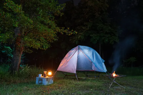 Geceleri ormanda kamp çadırları ve masaların üzerinde kahve yapma tesisleri.