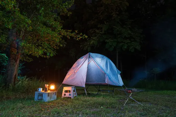 Geceleri ormanda kamp çadırları ve masaların üzerinde kahve yapma tesisleri.
