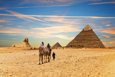 Mısır 'ın Büyük Piramitleri' nin önünde bedevelerle gezen turistler, Giza.
