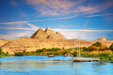 Nil 'e ve Aswan Çölü' ndeki piramitlerin yanındaki teknelere bakın, Mısır.