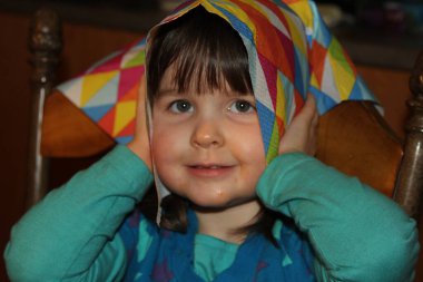 Bebek kafasında renkli bir peçete tutuyor.