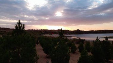 Gün batımında sakin bir göl üzerinde İHA uçuşu. Yavaş çekim