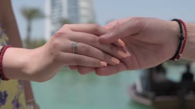 Erkek ve kadın elleri Dubai 'deki bir gökdelenin arka planında buluşuyor. Yavaş çekim