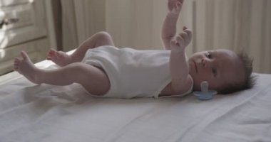 Beyaz bedenli yeni doğmuş erkek bebek beyaz çarşafın üzerinde yatıyor. Kapalı çekim, yakın çekim.