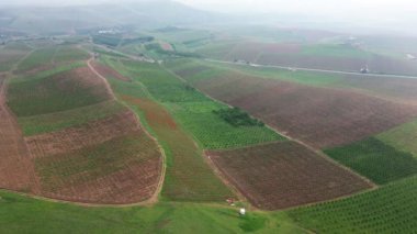 Tarlalar ve tepeler arasında bir kır yolu üzerinde İHA uçuşu